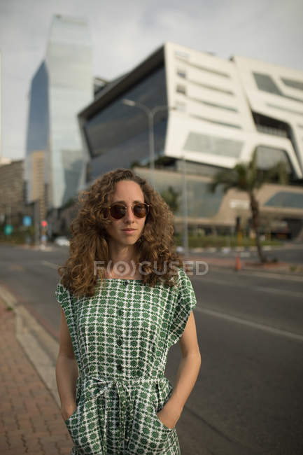 Mulher bonita em óculos de sol em pé na beira da estrada — Fotografia de Stock