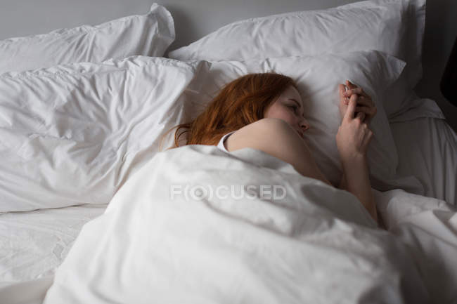 Mujer reflexiva relajarse en la cama en el dormitorio en casa - foto de stock