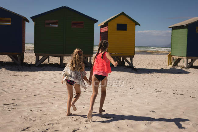 Rückansicht von Geschwistern, die an einem sonnigen Tag am Strand laufen — Stockfoto