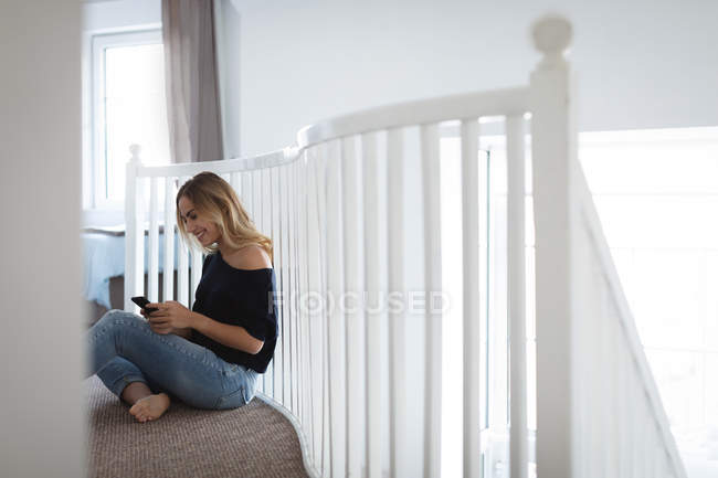Jeune femme utilisant un téléphone portable à la maison — Photo de stock