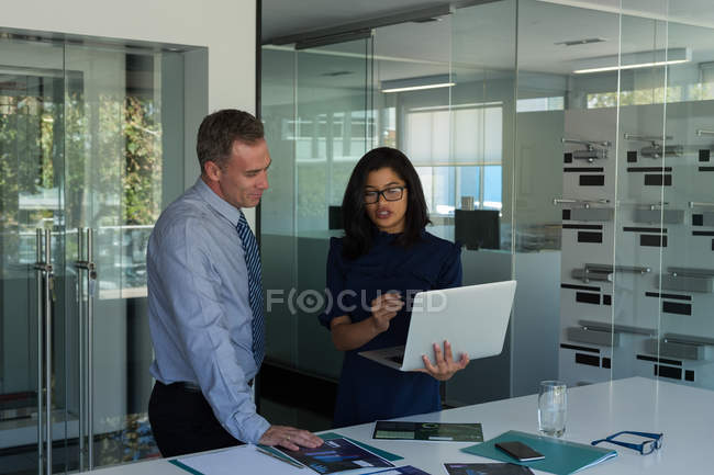 I colleghi di lavoro discutono sopra computer portatile in ufficio — Foto stock