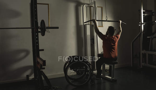Handicapped man working out at lat pulldown training at gym — Stock Photo