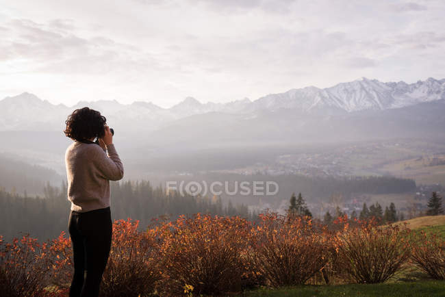 Mulher tirando foto com câmera digital no campo — Fotografia de Stock