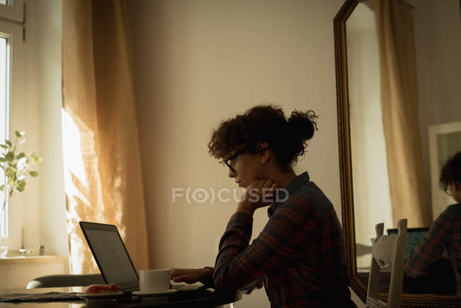 Mujer trabajando en el ordenador portátil en casa - foto de stock