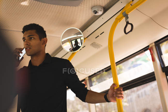 Jovem empresário falando no celular enquanto viaja no ônibus — Fotografia de Stock