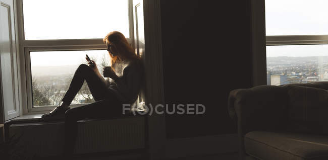 Frau benutzt Handy beim Kaffee zu Hause — Stockfoto