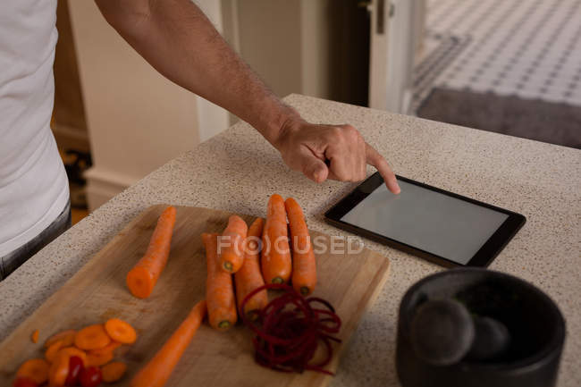 Homem sênior usando tablet digital na cozinha em casa — Fotografia de Stock