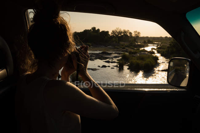 Mujer tomando fotos de la naturaleza con cámara digital en el coche - foto de stock