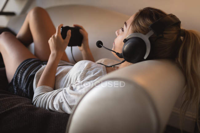 Donna che gioca al videogioco con auricolare in soggiorno a casa — Foto stock