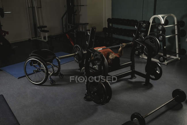 Инвалид делает упражнения на грудь на скамейке с штангой в тренажерном зале — стоковое фото