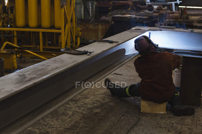 Vue arrière du soudeur réparant le cadre métallique dans l'atelier — Photo de stock