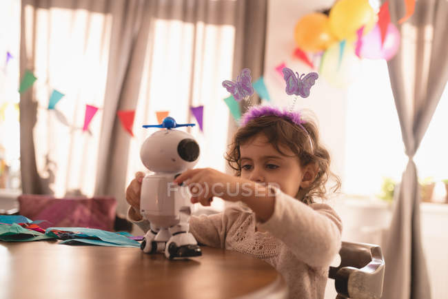 Menina brincando com robô brinquedo na sala de estar em casa . — Fotografia de Stock