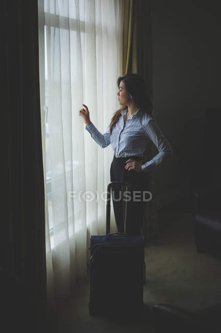 Mulher de negócios olhando através da janela no quarto de hotel — Fotografia de Stock
