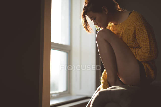 Mulher atenciosa relaxando perto da janela em casa — Fotografia de Stock