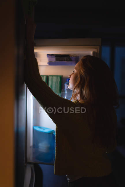 Женщина, открывающая холодильник дома — стоковое фото