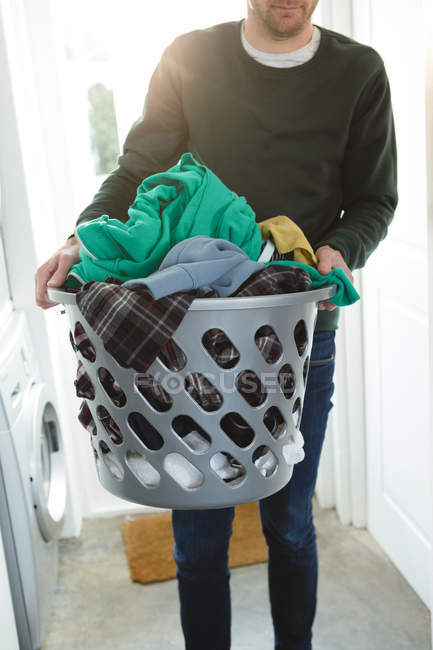 Homem segurando cesta de roupas de lavanderia em casa — Fotografia de Stock
