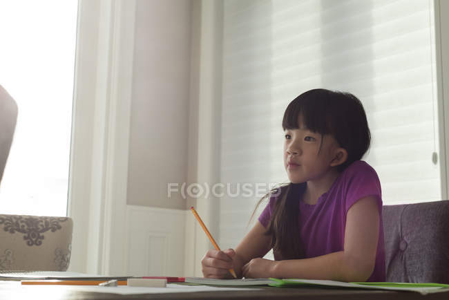 Adorável menina fazendo seu dever de casa em casa — Fotografia de Stock