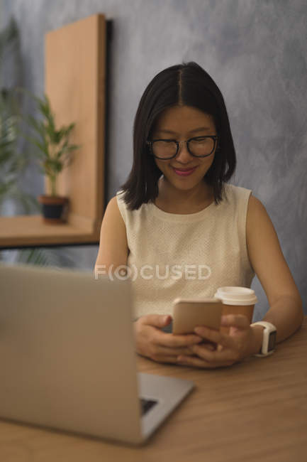 Businesswoman using mobile phone at desk in office — Stock Photo