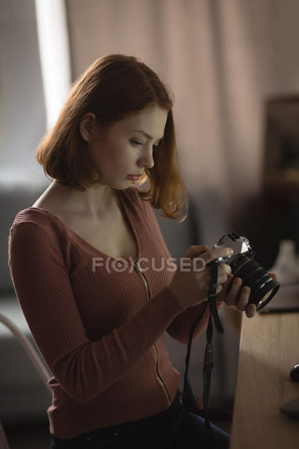 Femme examinant les caractéristiques de la caméra à la maison — Photo de stock