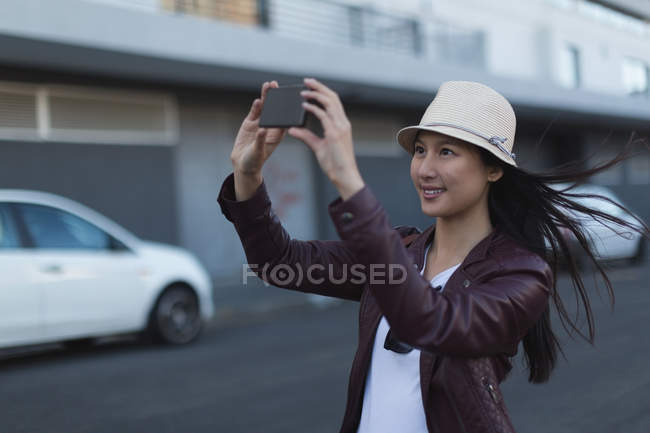 Woman taking photo with mobile phone in city street — Stock Photo