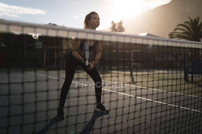 Giovane donna che pratica il tennis nel campo da tennis — Foto stock