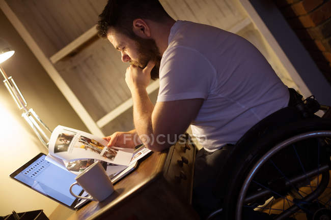Disabled man looking at documents while using laptop at home — Stock Photo