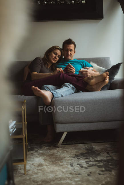Paar nutzt Handy und digitales Tablet im heimischen Wohnzimmer — Stockfoto