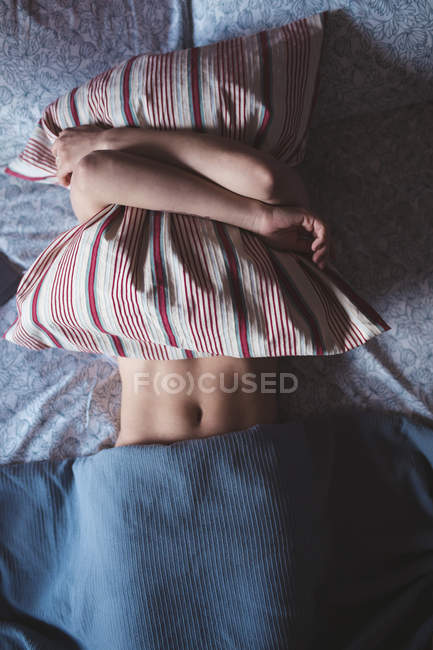 Женщина обнимает подушку, пока спит в спальне дома — стоковое фото