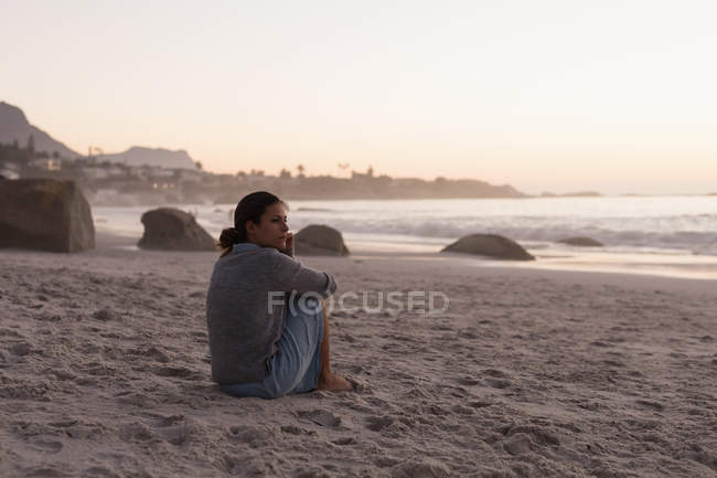 Mujer relajándose en la playa de arena al atardecer . - foto de stock