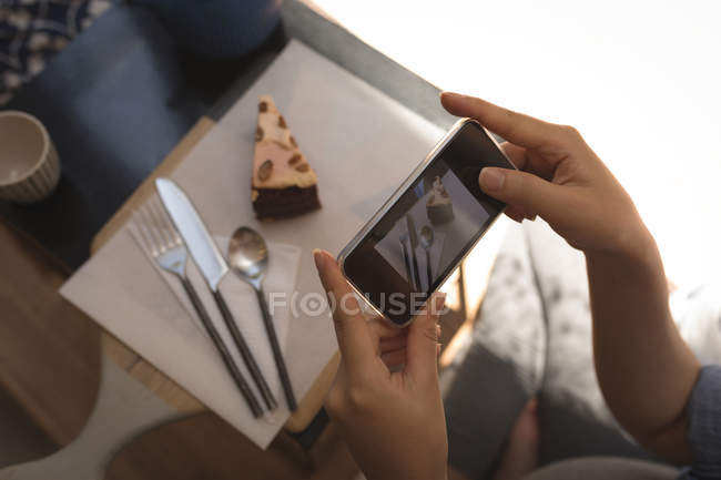 Mujer embarazada tomando fotos de pastelería con teléfono móvil en casa - foto de stock