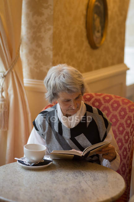 Mujer mayor leyendo un libro en casa - foto de stock
