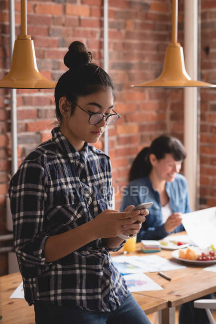 Жіночий керівник використовує мобільний телефон у творчому офісі — стокове фото