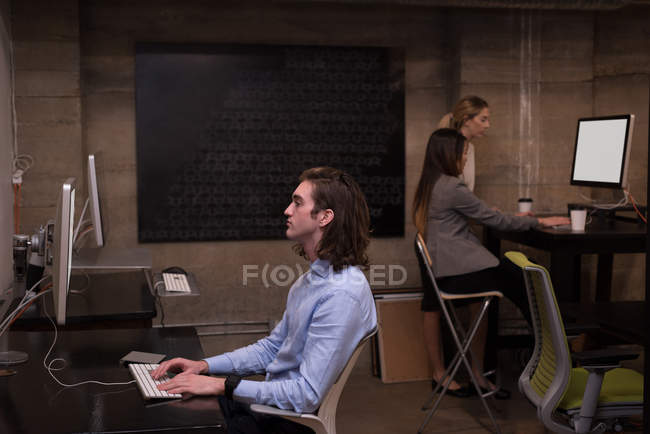 Male and female office workers using computers in office interior. — Stock Photo