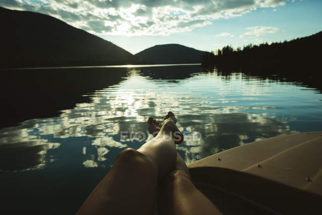 Низька частина людини, що розслабляється на човні в озері — стокове фото