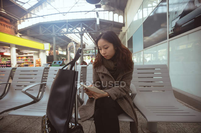 Mulher usando telefone celular na área de espera na estação ferroviária — Fotografia de Stock