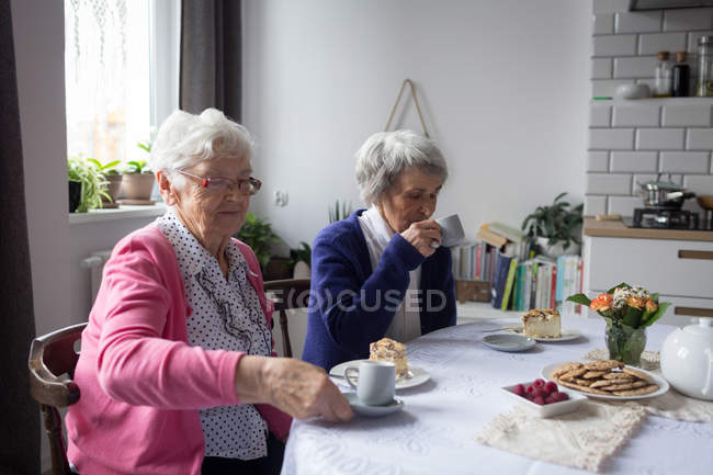Старшие друзья завтракают вместе дома — стоковое фото