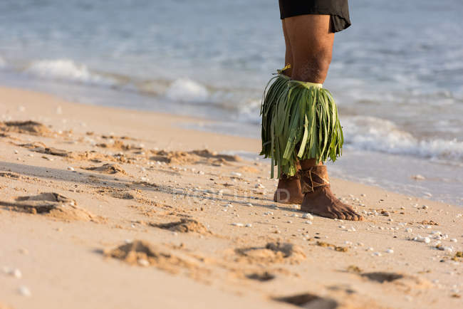Low section of male traditional Hawaiian performer standing at beach sand — Stock Photo