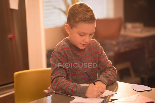 Мальчик рисует на бумаге дома — стоковое фото