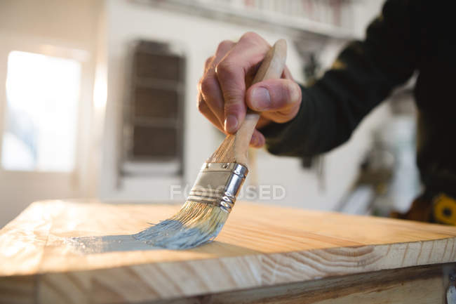 Macho carpinteiro pintando uma mesa na oficina — Fotografia de Stock