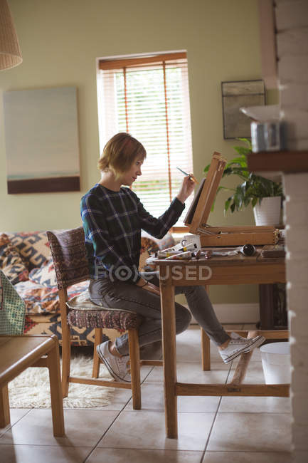 Женщина-художник рисует картину на холсте в гостиной на дому — стоковое фото