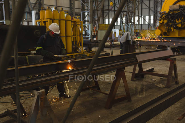 Welder repairing metal frame in workshop — Stock Photo