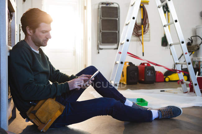 Мужской плотник с помощью мобильного телефона в мастерской — стоковое фото
