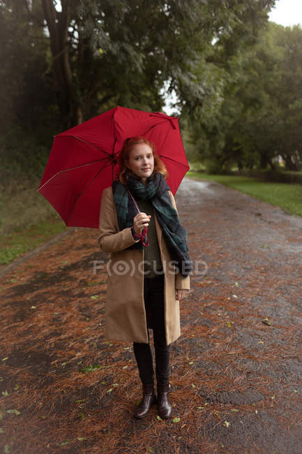 Jovem de pé com guarda-chuva no parque — Fotografia de Stock
