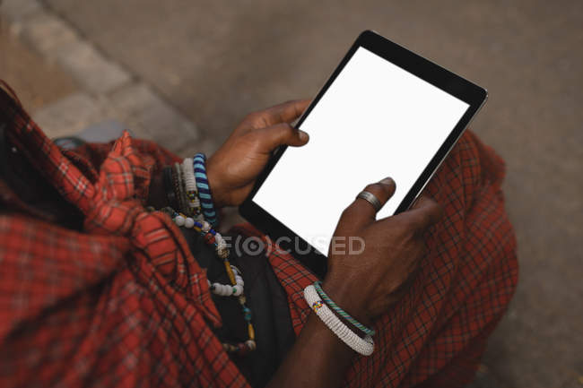 Mid section of maasai man in traditional clothing using digital tablet — Stock Photo