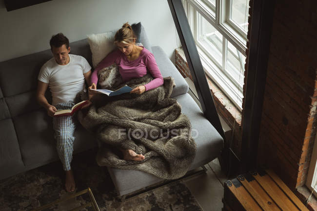 Пара читає книги у вітальні вдома — стокове фото