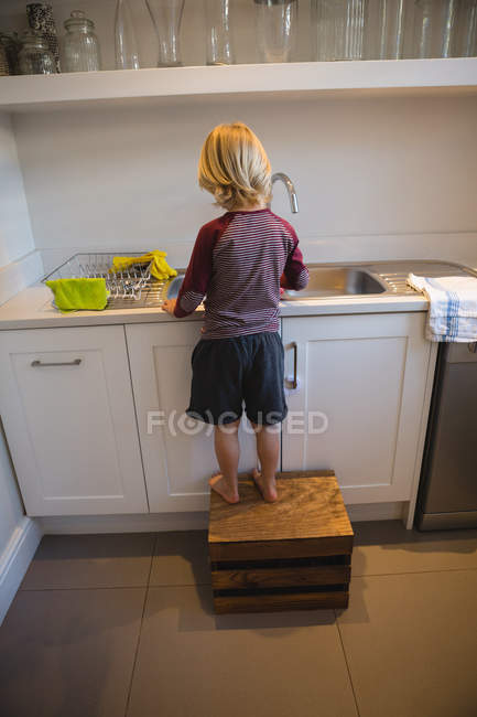 Vue arrière du garçon travaillant dans la cuisine à la maison — Photo de stock