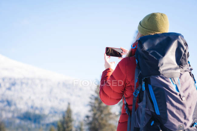Frau klickt im Winter ein Bild auf Smartphone — Stockfoto