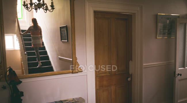 Вид сзади на женщину, идущую по лестнице домой — стоковое фото