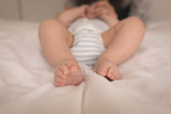 Close-up de bebê em terno de bebê deitado na cama em casa — Fotografia de Stock