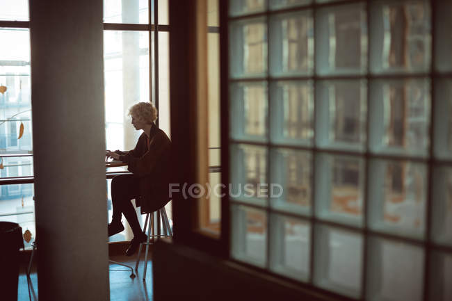 Mujer usando laptop en cafetería en la universidad - foto de stock